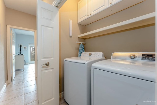 clothes washing area featuring cabinets, separate washer and dryer, and light tile patterned floors