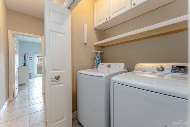 clothes washing area featuring cabinets, separate washer and dryer, and light tile patterned floors