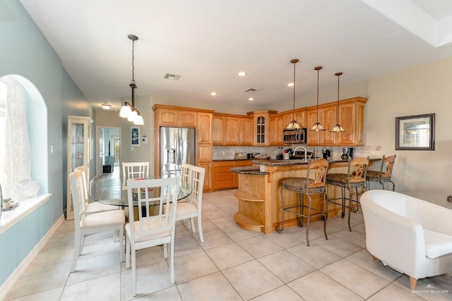 kitchen with kitchen peninsula, backsplash, a breakfast bar, stainless steel appliances, and light tile patterned floors