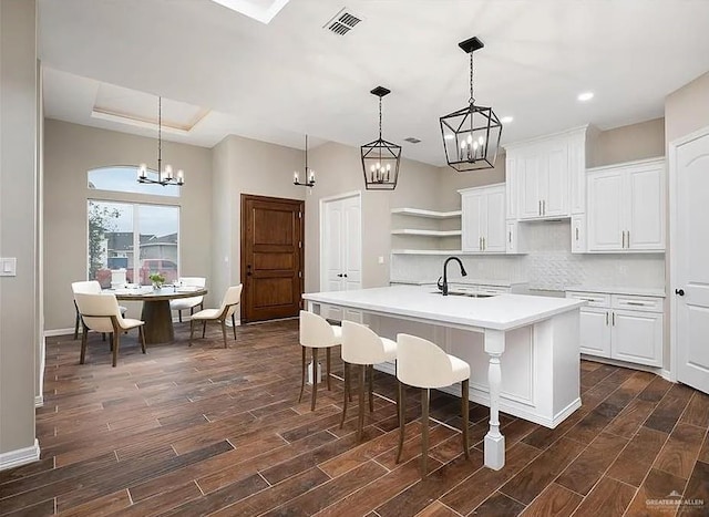 kitchen featuring light countertops, a sink, a kitchen island with sink, and pendant lighting