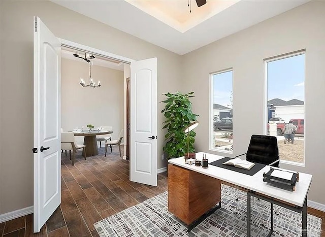 home office featuring ceiling fan with notable chandelier, wood finish floors, and baseboards