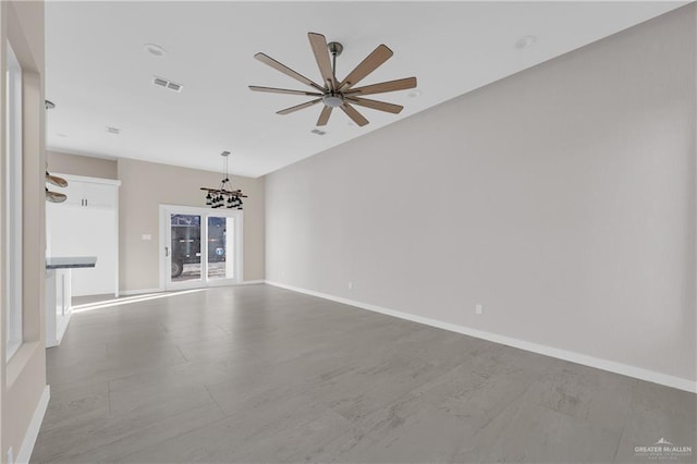 spare room with ceiling fan with notable chandelier, visible vents, and baseboards