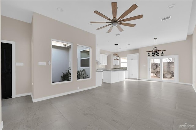 unfurnished living room with a sink, ceiling fan, visible vents, and baseboards