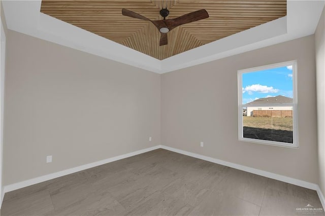 unfurnished room featuring baseboards, a tray ceiling, and a ceiling fan