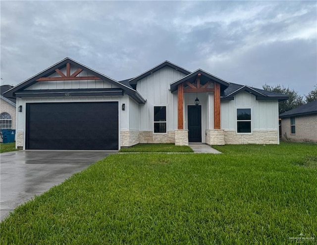 view of front of property with driveway, a front yard, an attached garage, and stone siding