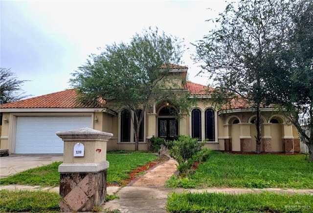 mediterranean / spanish home with stucco siding, a front yard, a tile roof, an attached garage, and concrete driveway