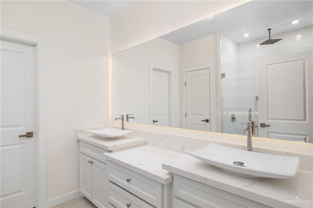 bathroom featuring double vanity, a shower stall, baseboards, and a sink