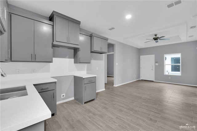 207 W Campeche Ave, Alton, TX 78573 - kitchen with gray cabinets, a ceiling fan, a raised ceiling, and baseboards