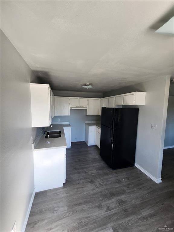 kitchen featuring white cabinetry, sink, dark hardwood / wood-style flooring, and black fridge