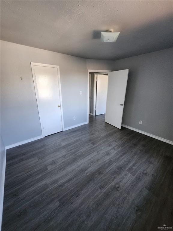 empty room with dark wood-type flooring and a textured ceiling