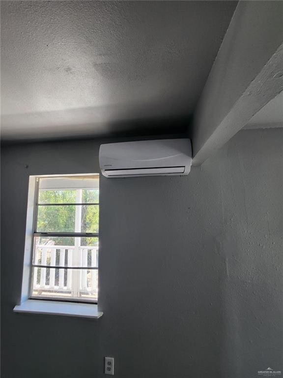 room details with a wall mounted air conditioner and a textured ceiling