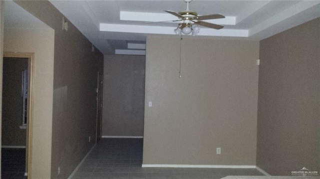 spare room with a tray ceiling and ceiling fan