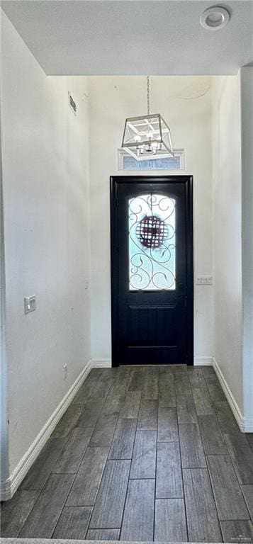 entryway with dark hardwood / wood-style flooring and a notable chandelier