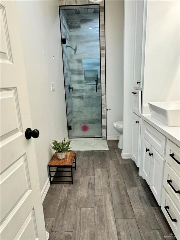 bathroom featuring hardwood / wood-style floors, vanity, a shower with door, and toilet