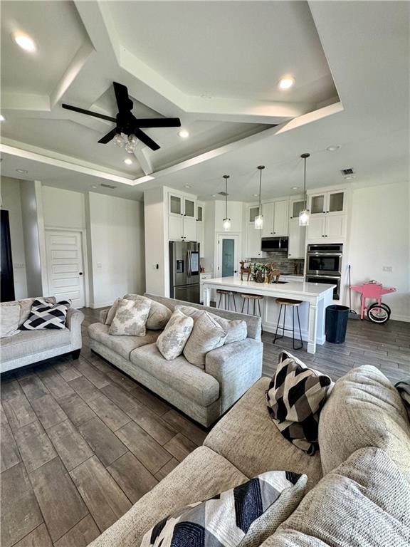 living room with beamed ceiling, dark hardwood / wood-style flooring, and ceiling fan