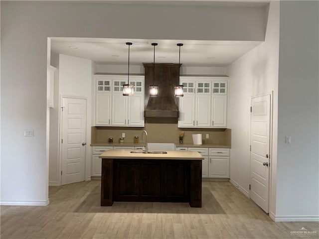 kitchen featuring pendant lighting, a center island with sink, white cabinetry, and sink