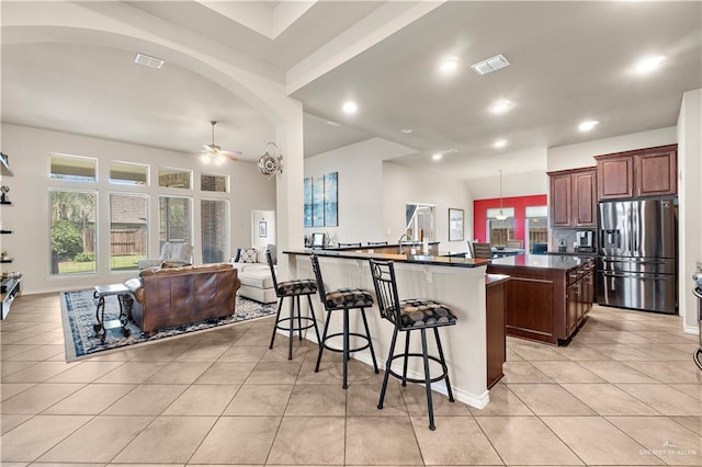 3606 Santa Lucia St, Mission, TX 78572 - kitchen with stainless steel fridge with ice dispenser, dark countertops, a kitchen island, ceiling fan, and light tile patterned flooring
