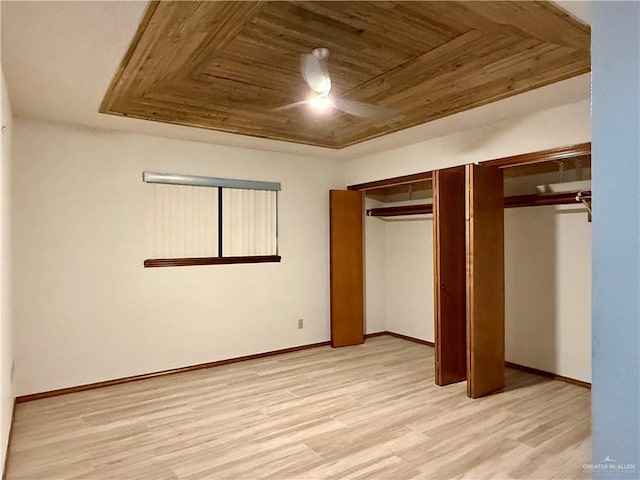 unfurnished bedroom featuring two closets, light wood-type flooring, a raised ceiling, and wood ceiling