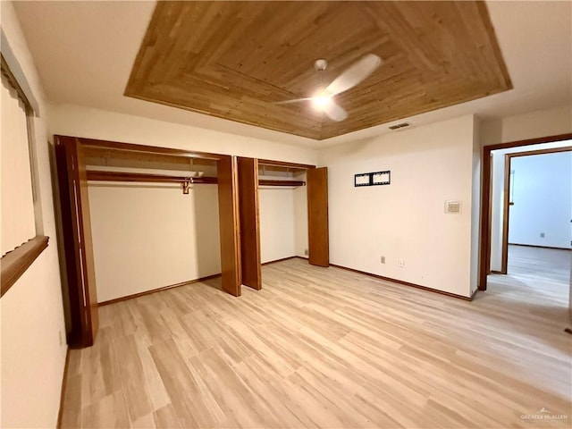 unfurnished bedroom with light wood finished floors, two closets, a raised ceiling, visible vents, and wooden ceiling