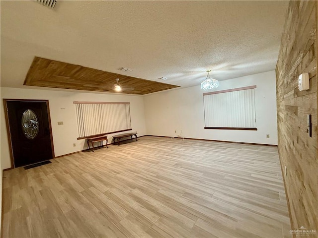 interior space featuring visible vents, a textured ceiling, baseboards, and wood finished floors