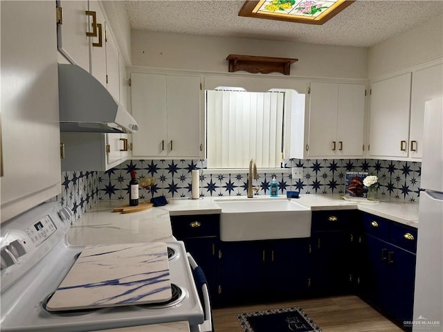 kitchen featuring light countertops, white cabinets, a sink, a textured ceiling, and white appliances