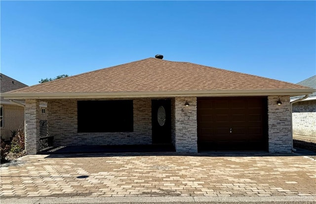 view of front of property with brick siding, roof with shingles, an attached garage, and decorative driveway