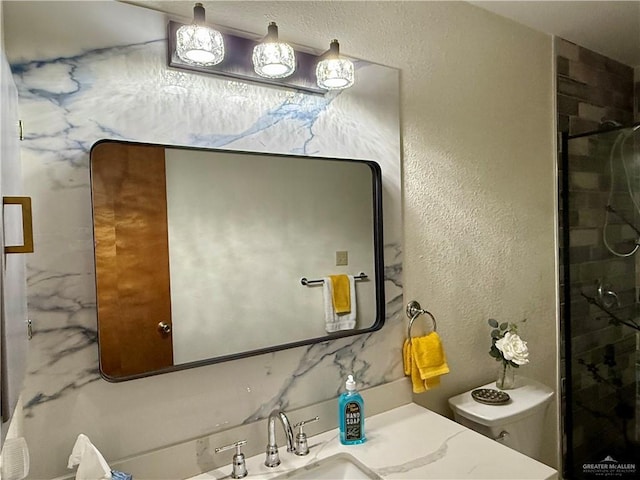 full bathroom with toilet, a stall shower, vanity, and a textured wall