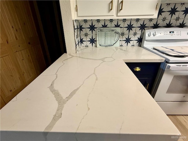 kitchen featuring white cabinets, white electric stove, and light stone countertops