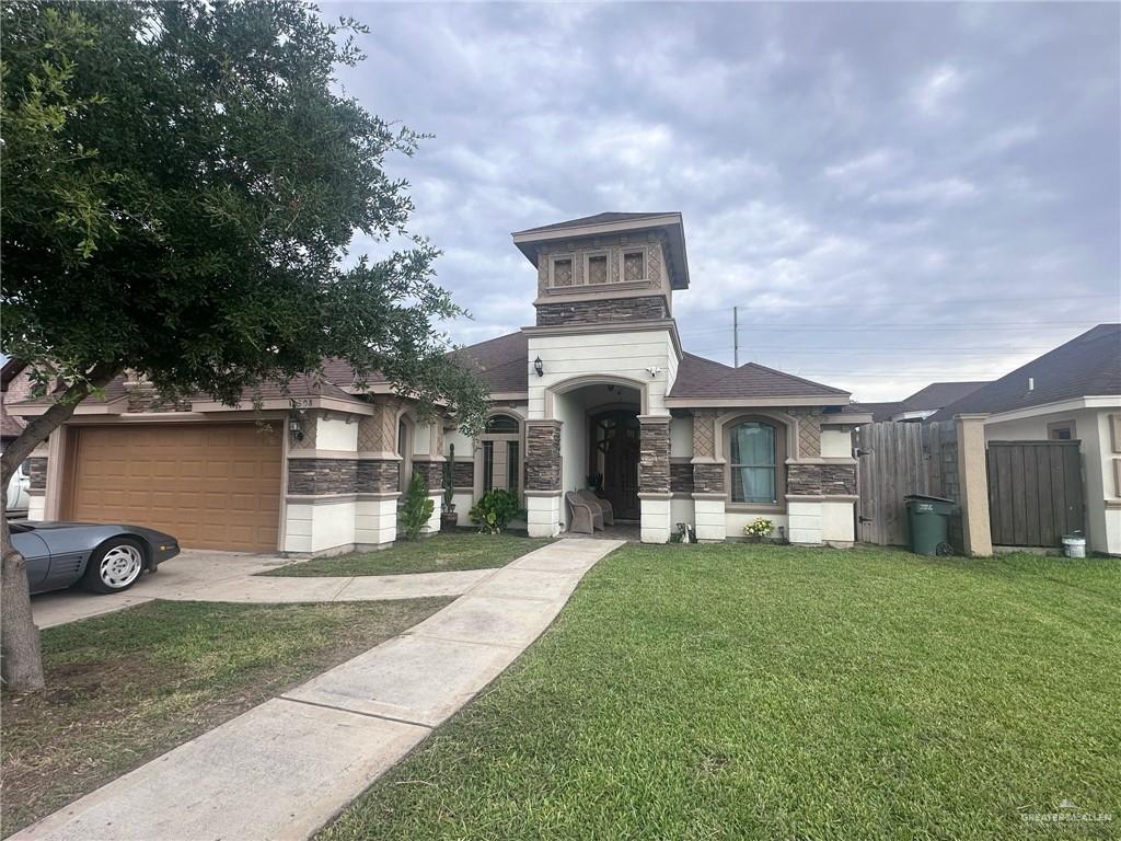 2308 Monte Grande Dr, San Juan, TX 78589 - view of front of home featuring stone siding, driveway, and an attached garage