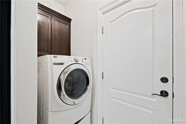 clothes washing area with washer / clothes dryer and cabinets