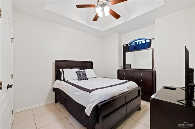 tiled bedroom featuring a raised ceiling and ceiling fan