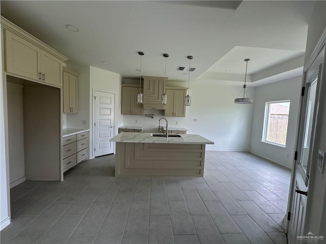 408 Janet Cir N, La Feria, TX 78559 - kitchen featuring a kitchen island with sink, cream cabinets, hanging light fixtures, light stone counters, and wood finished floors