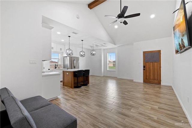 living room featuring sink, lofted ceiling with beams, and ceiling fan with notable chandelier