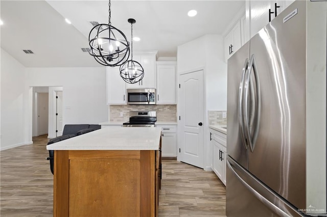 kitchen featuring white cabinetry, hanging light fixtures, a center island, and stainless steel appliances