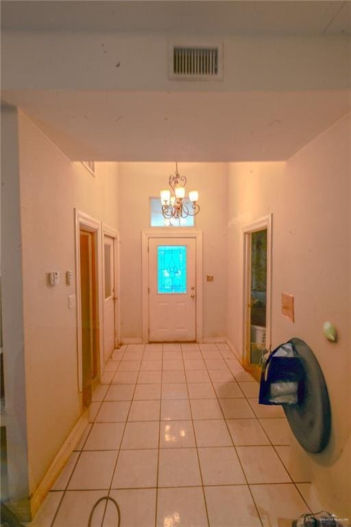 entryway with light tile patterned floors and an inviting chandelier