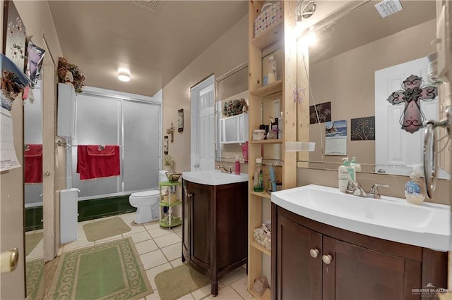 bathroom with toilet, vanity, tile patterned floors, and a shower with shower door