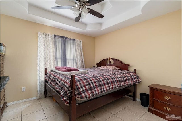 tiled bedroom featuring a tray ceiling, baseboards, and ceiling fan