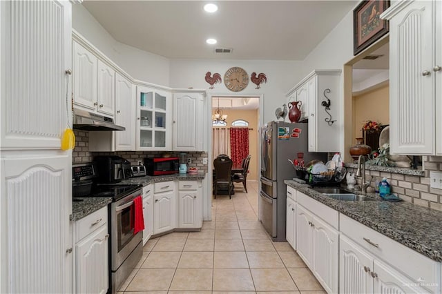 kitchen featuring appliances with stainless steel finishes, under cabinet range hood, a sink, backsplash, and light tile patterned floors