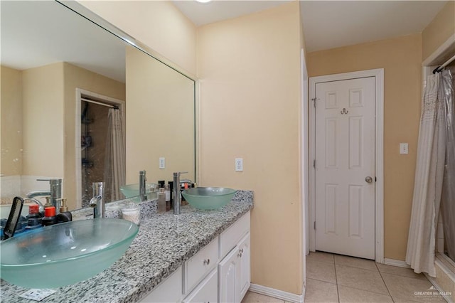 bathroom with tile patterned flooring, double vanity, baseboards, and curtained shower