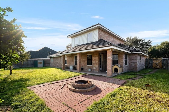 rear view of house featuring a patio area, a yard, and a fire pit