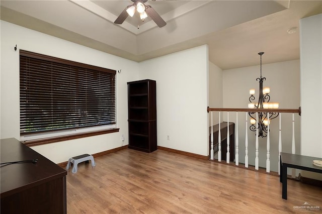 spare room with ceiling fan with notable chandelier and wood-type flooring