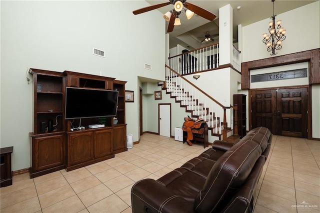 living room with a high ceiling, ceiling fan with notable chandelier, and light tile patterned floors