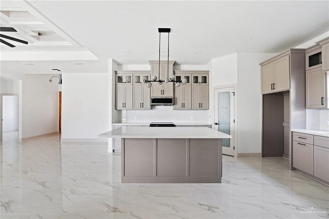 kitchen featuring marble finish floor, a kitchen island, light countertops, glass insert cabinets, and a chandelier