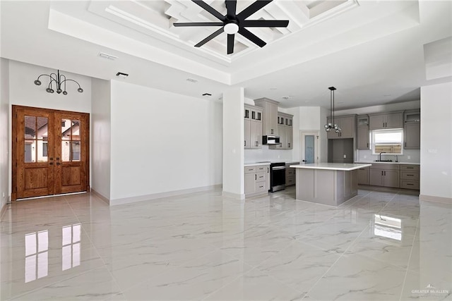 kitchen featuring a tray ceiling, gray cabinets, appliances with stainless steel finishes, marble finish floor, and open floor plan