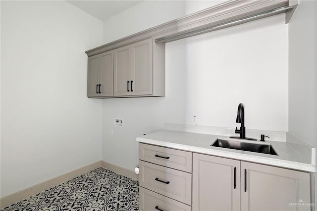 laundry area with a sink, cabinet space, light tile patterned floors, baseboards, and hookup for a washing machine