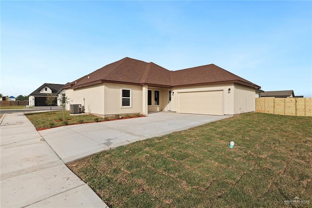 single story home featuring fence, concrete driveway, a front yard, central AC unit, and an attached garage