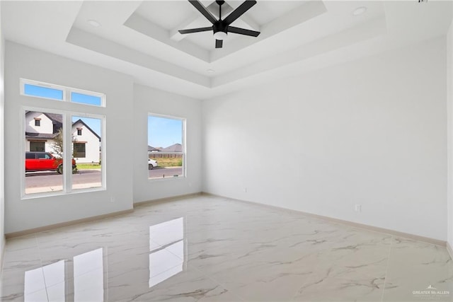 unfurnished room with marble finish floor, baseboards, a tray ceiling, and ceiling fan