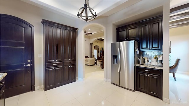 843 Brady Ave, Alamo, TX 78516 - interior space with tasteful backsplash, dark brown cabinets, stainless steel fridge, arched walkways, and light stone countertops