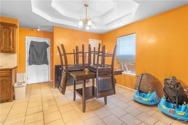 tiled dining area with a raised ceiling and an inviting chandelier