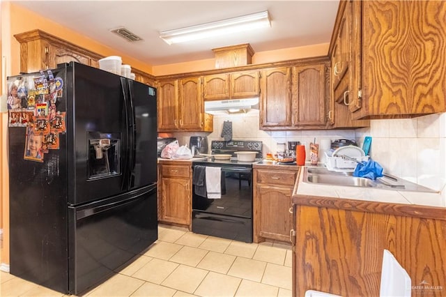 kitchen with tasteful backsplash, light tile patterned floors, and black appliances